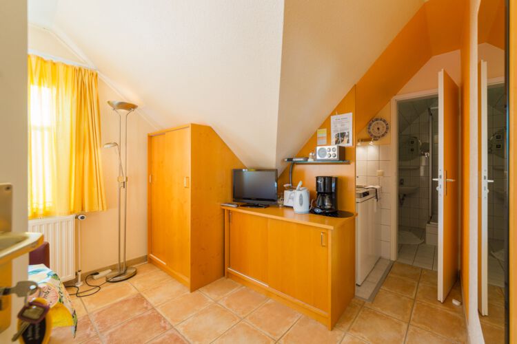 Eingang zur Ferienwohnung, Sideboard mit Küchenutensilien, kleine Kochnische mit angrenzendem Bad, TV