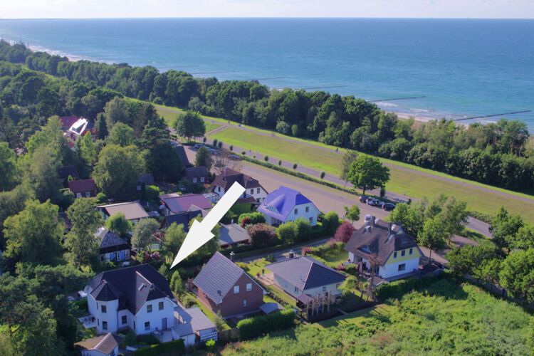 Luftaufnahme vom Ferienhaus mit 4 Ferienwohnungen, eingebettet in viel Gruen, im Hintergrund der Deich und die Ostsee