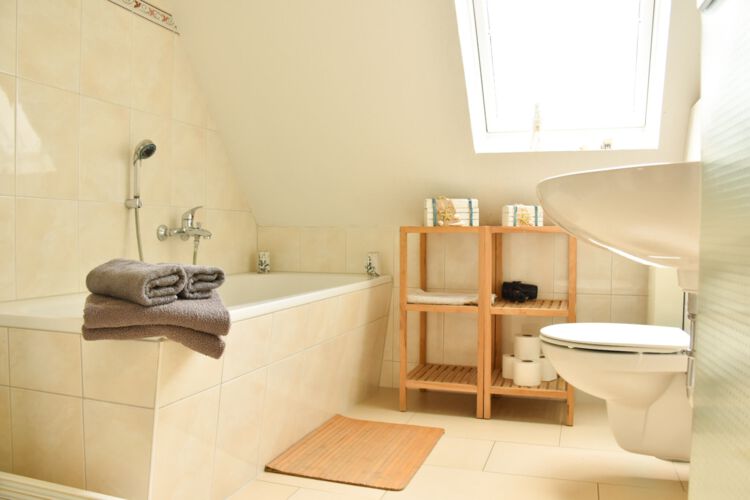 Badezimmer im 1. OG mit Badewanne, Waschbecken, WC, Holzregalen und Dachfenster