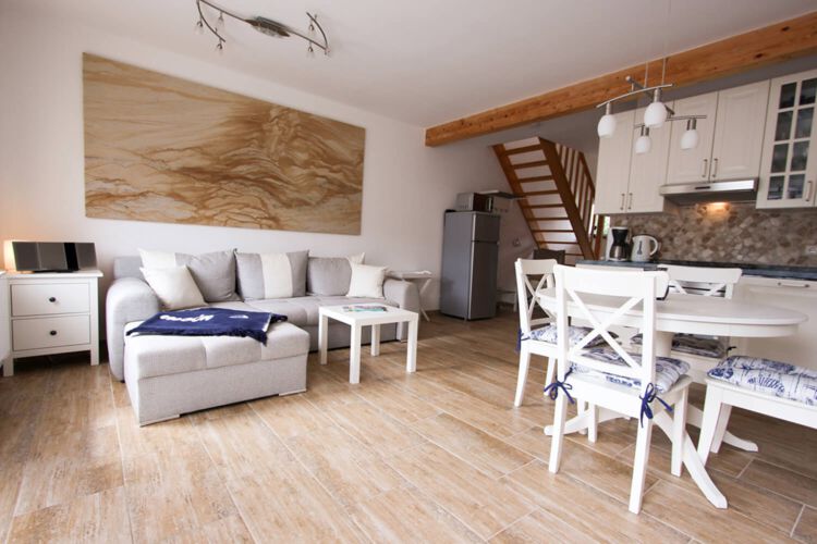 helles Sofa mit kleinem Wohnzimmertisch auf braunen Fliesenboden