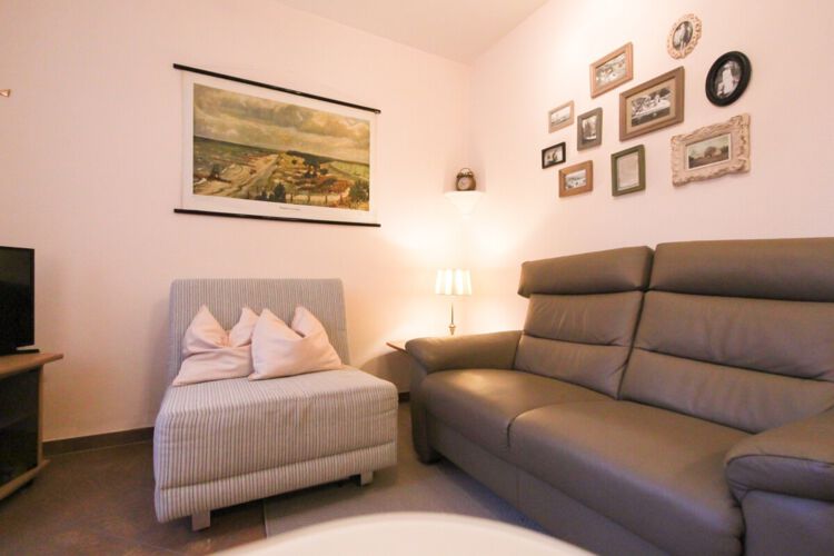 Wohnbereich mit Sofa, Schlafseesel, kleiner Tischlampe und Flatscreen-TV, verschiedene Bilder an der Wand