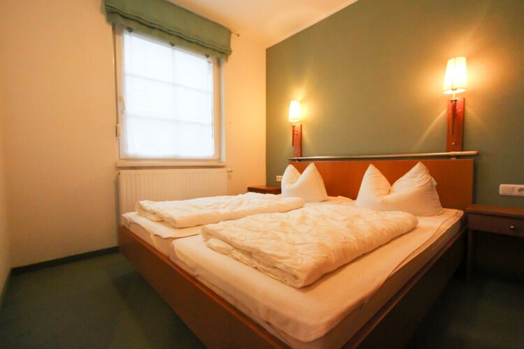 gemütliches Doppelbett im separaten Schlafzimmer mit Fenster, Wandleuchten und Nachttischen